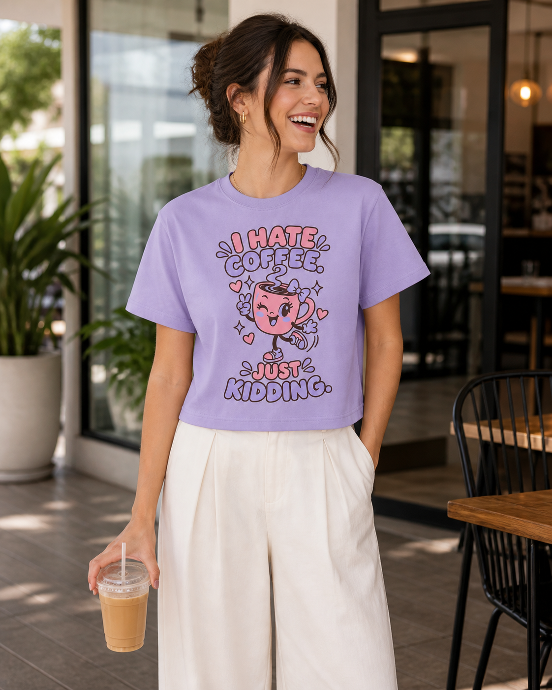 Woman wearing the I Hate Coffee cropped tee at a café